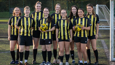 A group of women in football uniforms stand together