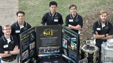 A group of male students standing behind a scientific presentation