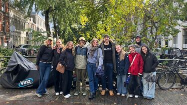 Mixed group of people on a Dutch canal. Lots of green trees line the image