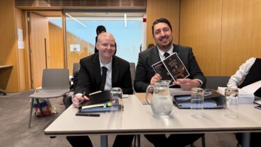 Two of the team, sitting on a table with files.