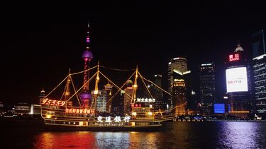 A traditional looking Chinese ship light up with neon lighting at night