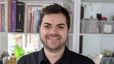 A smiling man standing in front of a bookshelf