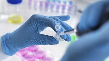 Blue gloves placing liquid in a pipette 
