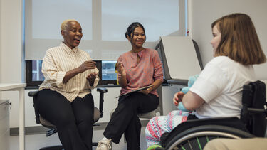 Girl in a wheelchair with doctors, smiling