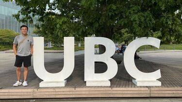 Student outside beside UBC logo