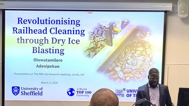 Researcher presenting in front of a screen that says 'revolutionising railhead cleaning through dry ice blasting'