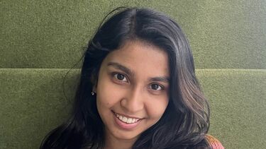 A smiling woman standing against a green wall