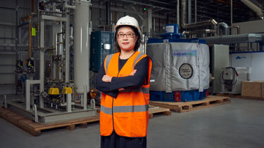 Lenny Koh stood in warehouse in front of machinery