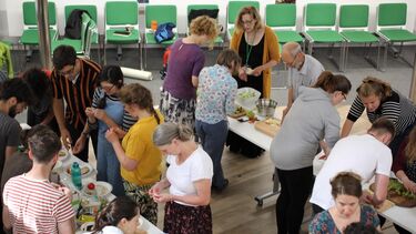 Groups of people standing around tables sharing food