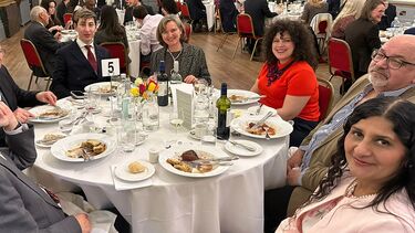 PhD student and his supervisors sitting round a table at an awards ceremony