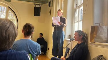 Dr Grace Josephs stands on a chair to deliver a monologue at Battersea Arts Centre, as part of her ‘Open Scholar’ work-in-progress performance with Extant.