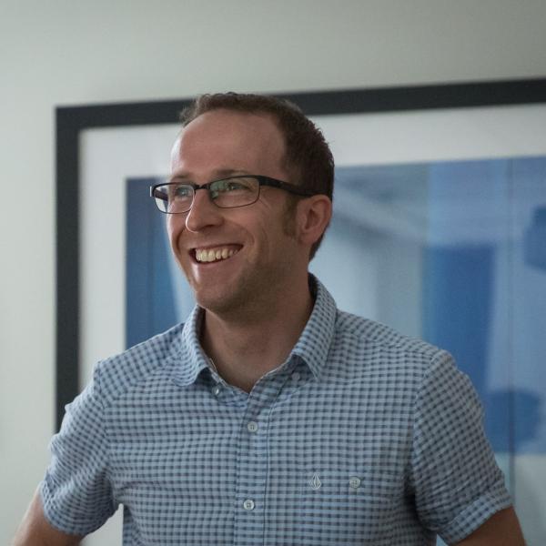 Profile picture of Smiling male member of staff in blue checked shirt