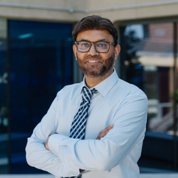 Profile picture of Sajid Bashir wearing a blue shirt and blue striped tie.