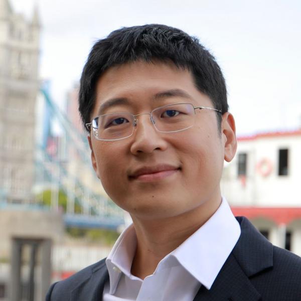 Profile picture of Image of a dark haired asian man wearing glasses, and a suit. He is outside and is smiling at the camera.