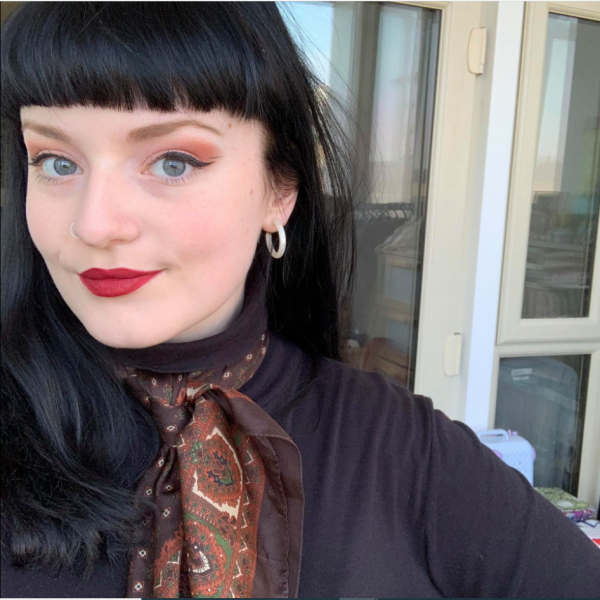 Profile picture of A young woman with black hair, red lipstick and a brown paisley scarf