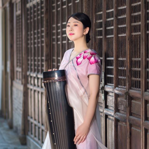 Profile picture of Profile picture of Shu Jiang holding her instrument in a white and purple dress. 