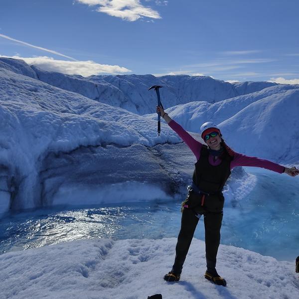 Profile picture of Sian Thorpe with arms outstretched standing on a glacier