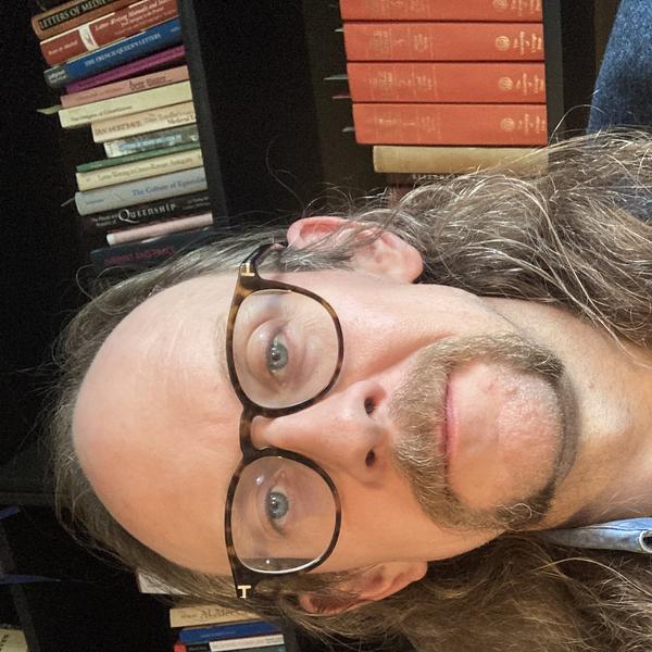 Profile picture of Dr Graham WIlliamson sat in front of a bookshelf facing forward