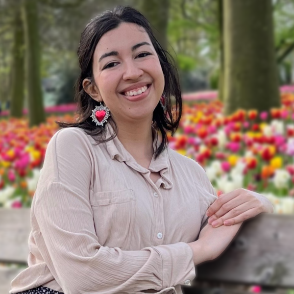 Profile picture of Maria Jimena Flores sat on a bench in front of flowers