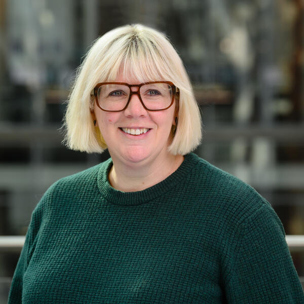 Profile picture of Headshot of a woman wearing a green jumper and glasses
