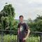 Student stood smiling in front of some railings with greenery in the background