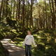 A female student stands on a path in a woodland and smiles towards the camera.