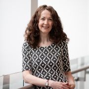 A head and shoulders photograph of Caroline Oates stood on the mezzanine in the Management School.