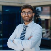 Sajid Bashir wearing a blue shirt and blue striped tie.