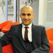 Ahmad Abras sat down on a red chair wearing a suit.