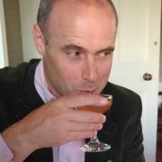 A photo of Dominic Gregory sipping a drink at a table.