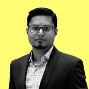 Tanvir Hasan in a suit against a yellow background