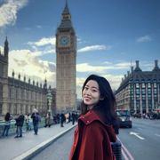 A photo of Xi (Helen) Chen where she is stood outside against a backdrop of the Houses of Parliament in London.