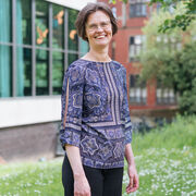 Rosanna stands on a grass bank with a building behind her 