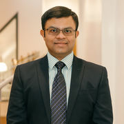 Avik Mukherjee wearing a black suit and striped green shirt.