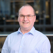 Portrait of academic with blue shirt, with glasses, smiling