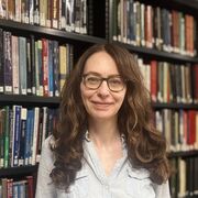 Iona stands in front of book shelves
