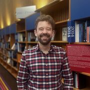 Matt stands in front of the Author's Showcase in Western Bank Library 