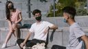 Three young people sit outside while wearing face masks