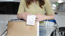 A person reading a receipt whilst pushing a shopping trolley