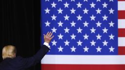 Donald trump waving in front of an american flag