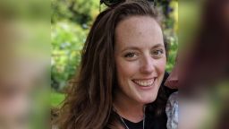 PhD student Sarah Linn smiles at camera while holding child