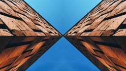Two buildings intersect at angles against the blue sky