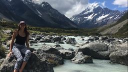 Laura Tracey sat on a rock in front of some mountains and a river