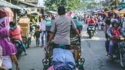 Man cycling through market in Indonesia