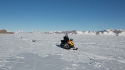 A snowmobile travelling across Antarctica with a radar survey attached to locate and examine subglacial lakes