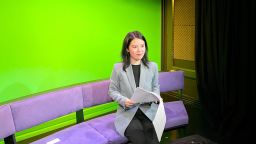 Cici chow, holding a script and sat on a purple sofa in a tv studio