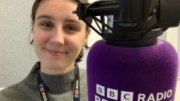 Maisie Marston smiling next to a BBC radio microphone.