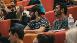 A close up of people sat in a lecture theatre smiling at an event in a previous year's Festival of Social Sciences