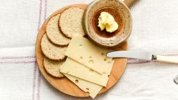 Crackers and cheese on a circular wooden board as seen from above