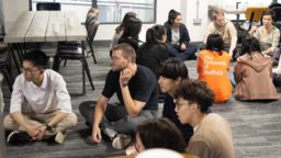 Students sitting in groups cross-legged on the floor